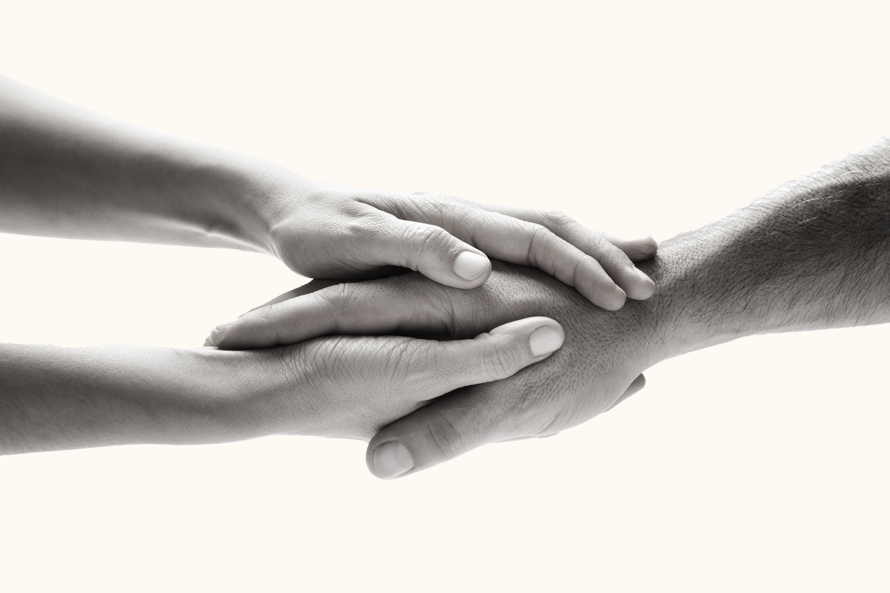 Les deux mains d’une personne entourant la main d’Une autre personne.